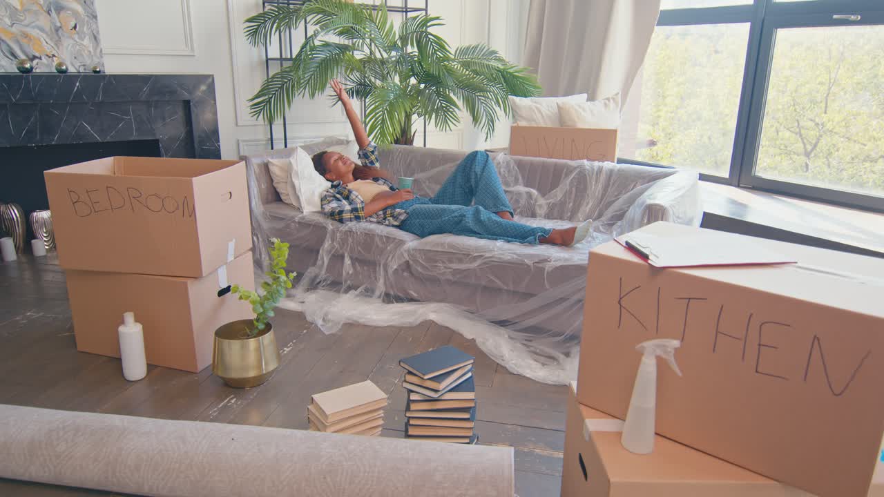 joven mujer afroamericana sonriente está feliz de moverse y acostarse en el sofá