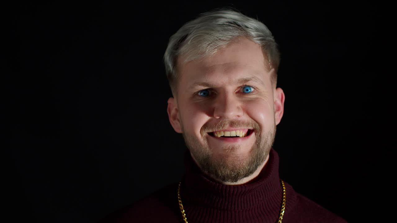 un joven elegante y sonriente con ojos azules mirando a la cámara, una sonrisa encantadora, un guiño, un parpadeo, un coqueteo