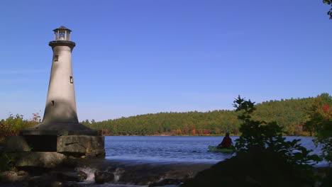 a pov shot from a kayak passing a remote lighthouse in new england