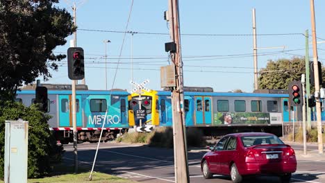 train crossing with waiting car and pedestrian