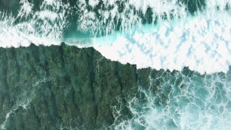 static top down view of waves breaking on shallow fringing reef in ocean water, angled water