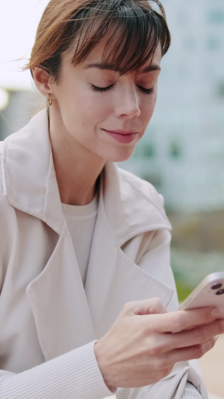 Giovane donna che usa lo smartphone all'aperto con espressione concentrata