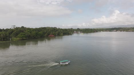 Barco-Con-Turistas-En-El-Río-Dulce-Cerca-Del-Castillo-De-San-Felipe,-Aéreo