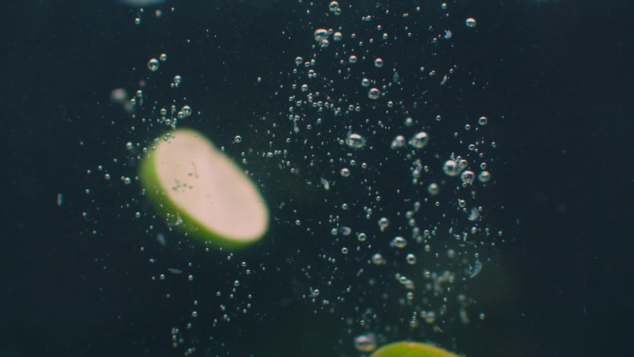 anillos de cal bajo el agua con burbujas de aire y en cámara lenta. fresco y jugoso vegetariano saludable.