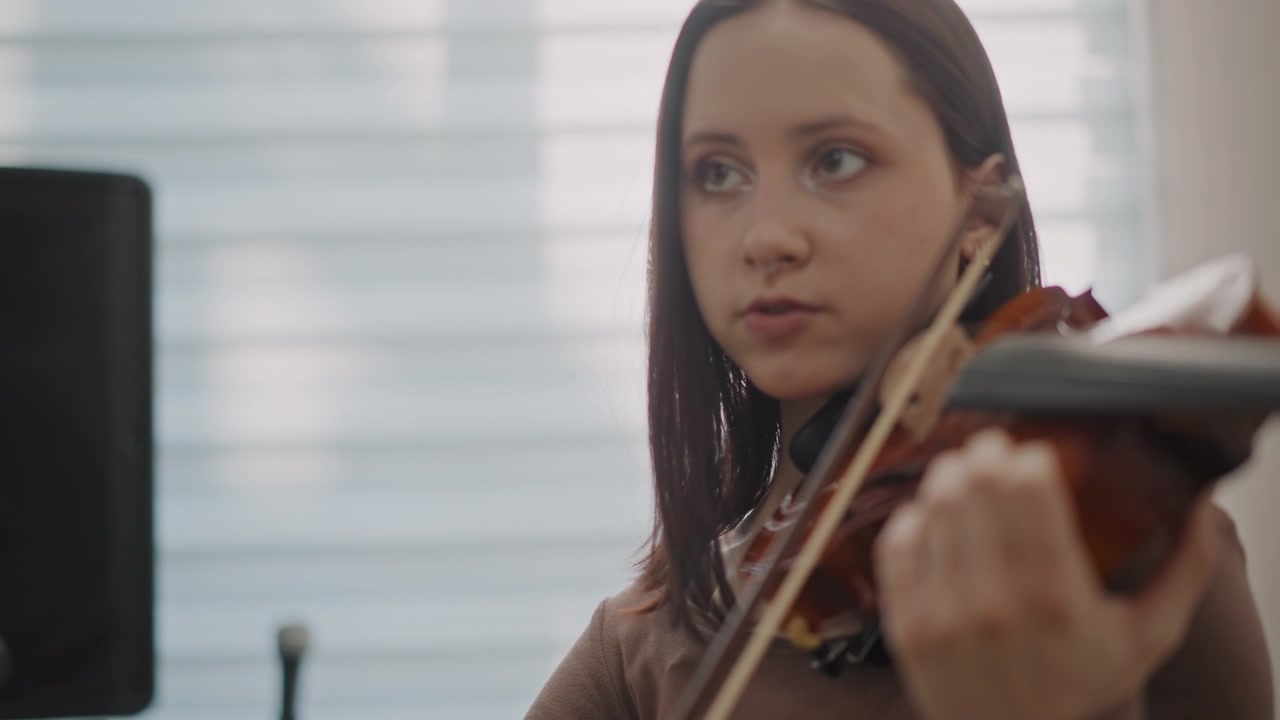 Musicista donna si concentra durante la pratica. Primo piano di una donna che suona il violino con concentrazione. Scena dettagliata di una musicista in prova che si concentra sulle sfumature musicali e sull'esecuzione tecnica