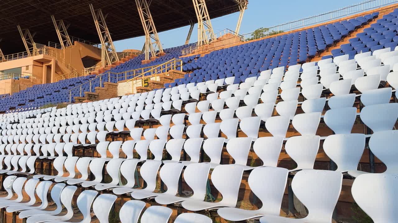 Curved white stadium chairs arranged in rows at outdoor sports venue