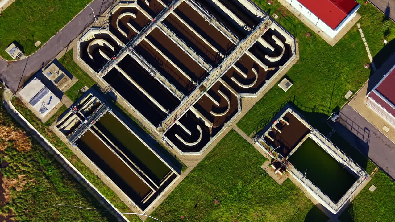 Water treatment facility with multiple tanks and green space visible from above during daytime in a clear weather setting