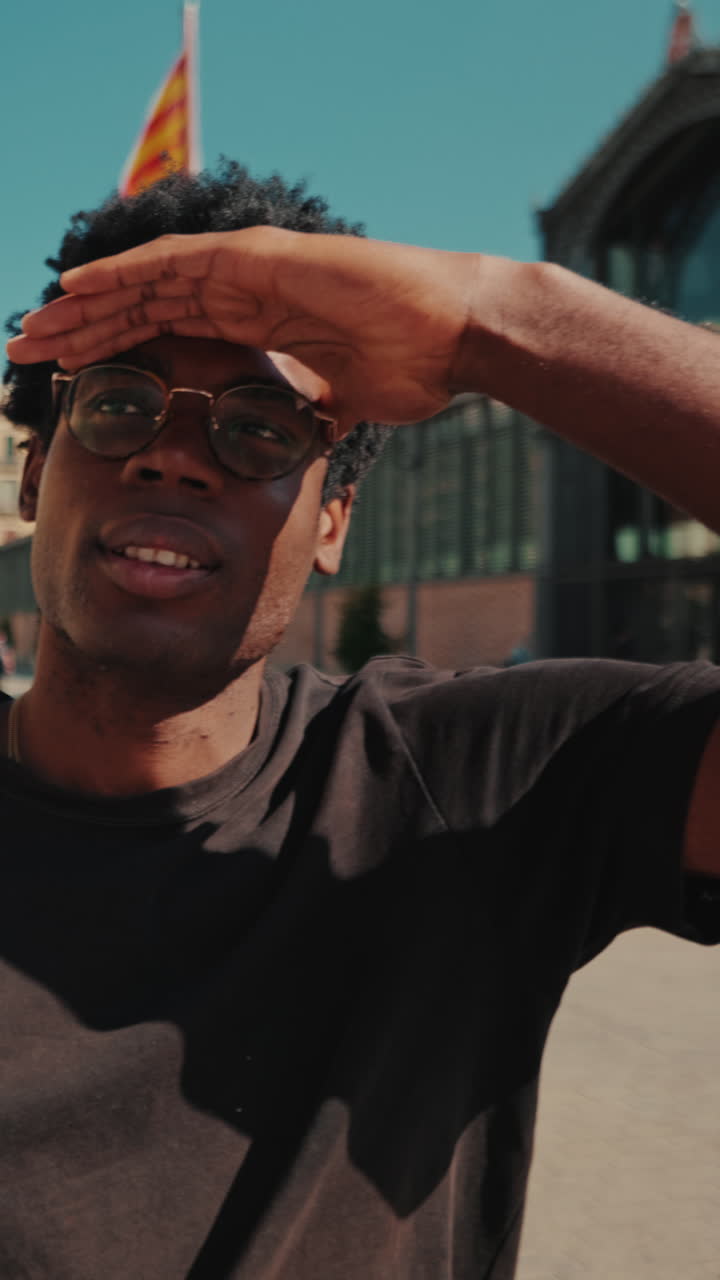 Young Black Man Shielding Eyes from Sun in City