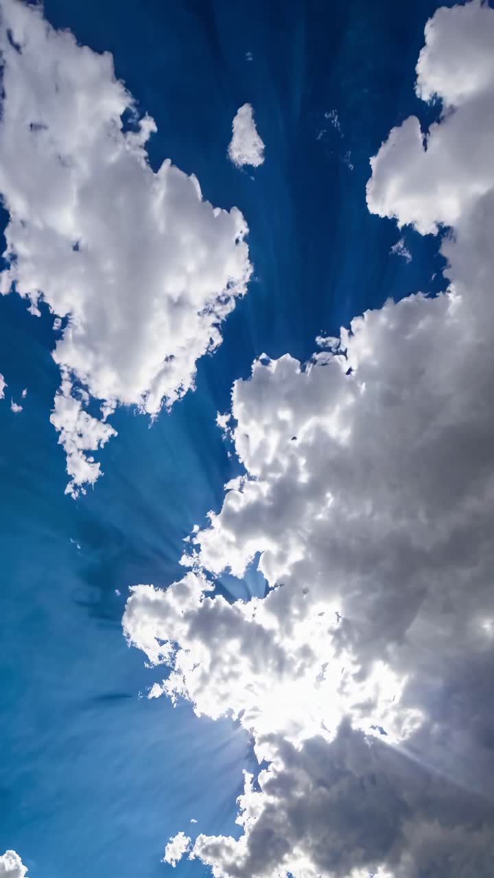 A dynamic upward angle captures fluffy clouds against a vibrant blue sky, creating a serene