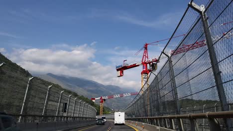 vehicles pass under a construction crane on a highway