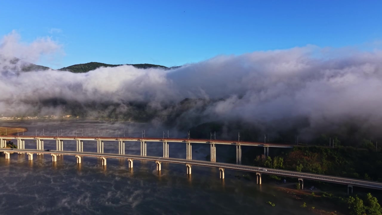 早朝、霧に覆われた川と橋、背景に山々が広がる風光明媚な風景