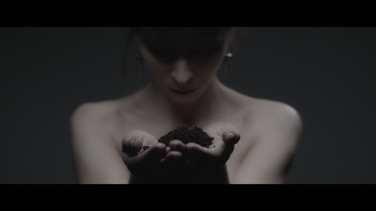 A woman dressed as mother nature holds soil in her hands