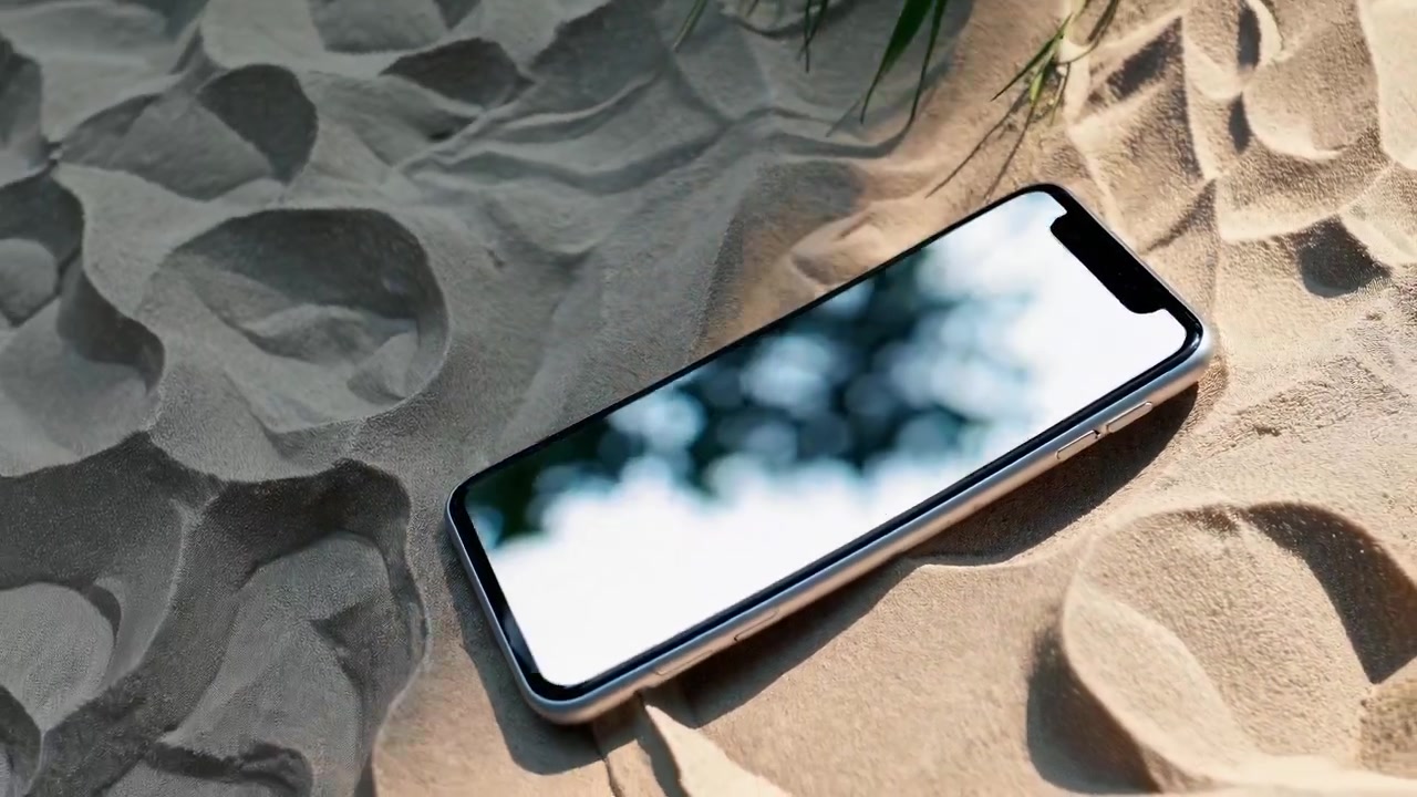 Roterende smartphone mockup med tom skærm på sandstrand