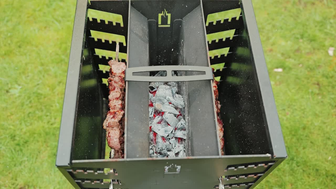 Slow motion overhead view of meat roasting on home grill with glowing coals
