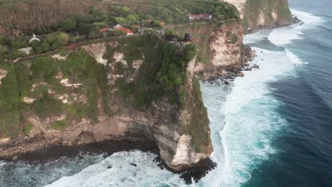 Luftaufnahme-Des-Wunderschönen-Uluwatu-Tempels-Auf-Einer-Hohen-Klippe-Mit-Meereswellen-In-Bali,-Indonesien