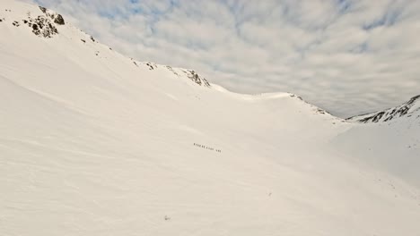 People-hiking-on-snowy-mountains-in-Norway,-aerial-distance-view