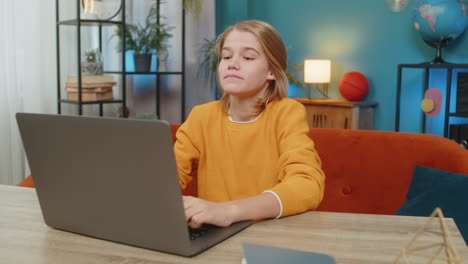 teenager boy enthusiastically playing online game on laptop celebrating victory on couch at home