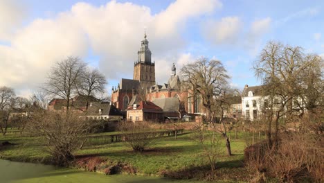 Timelapse-Del-Paisaje-Urbano-Con-Nubes-Pasando-Por-Encima-De-La-Pintoresca-Torre-De-La-Iglesia-Medieval-De-Walburgiskerk-Creando-Patrones-En-Los-Exuberantes-Jardines-En-El-Primer-Plano-De-La-Ciudad-Histórica-Holandesa-Zutphen