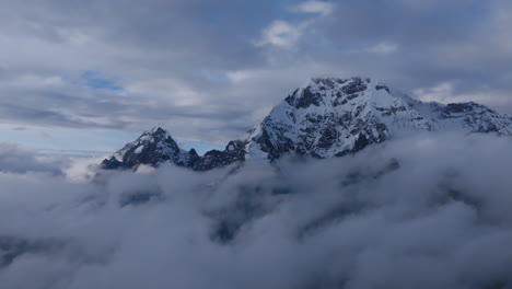 Imágenes-Aéreas-Que-Se-Elevan-Lentamente-Sobre-Un-Grupo-De-Nubes-De-Bajo-Nivel-Para-Revelar-La-Cima-De-Una-Montaña-Cubierta-De-Nieve-En-El-Ausangate-En-Perú.