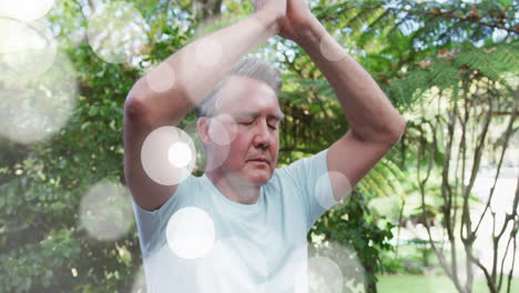 mature man practicing yoga in lush garden, featuring floating light flares enhancing wellness