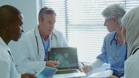 Front-view-of-Multi-ethnic-doctors-discussing-over-laptop-in-hospital