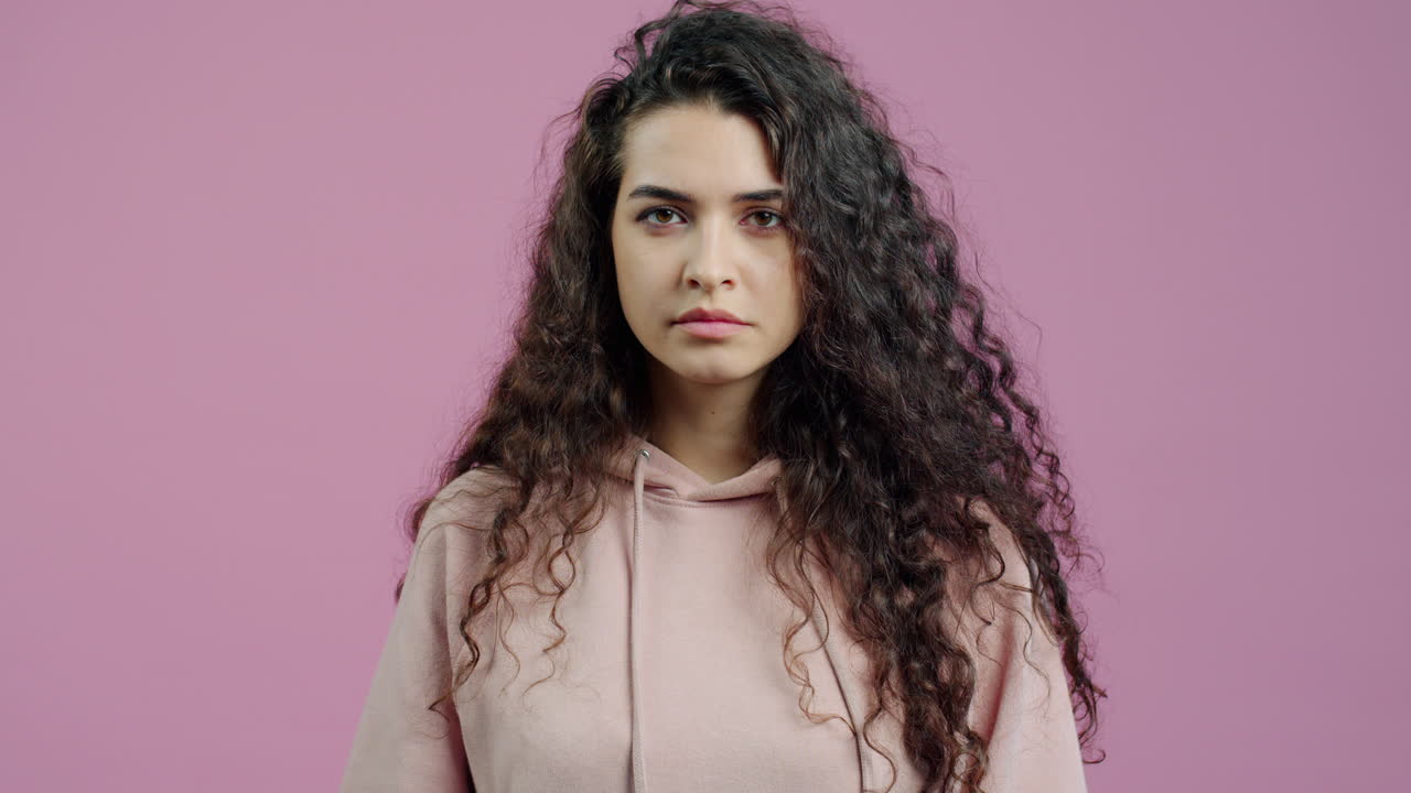 Woman with curly hair in a hoodie, expressing disapproval