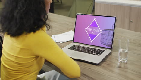 Biracial-woman-at-table-using-laptop,-online-shopping-during-cyber-monday-sale,-slow-motion