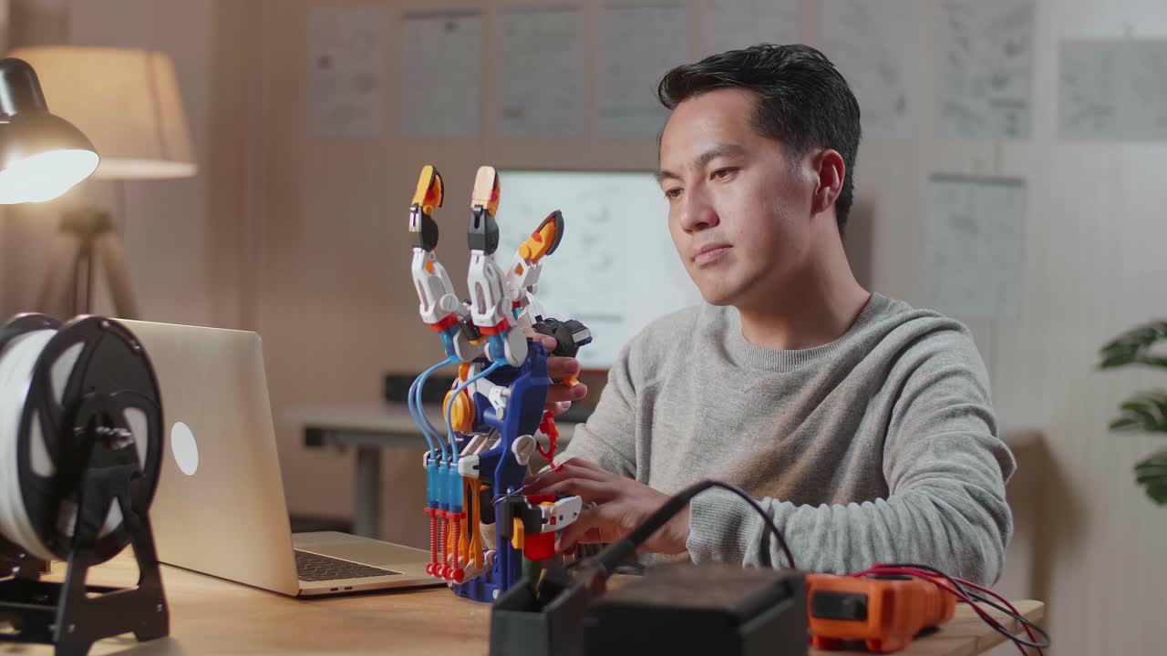 Man building and repairing a robotic arm at his desk