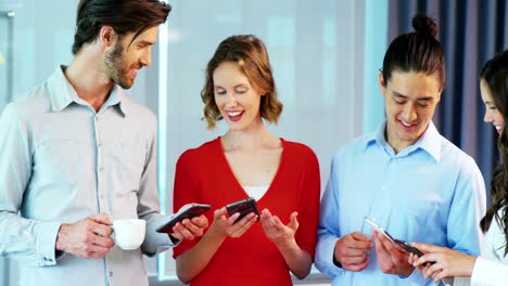 colegas de negocios sonrientes usando el teléfono móvil