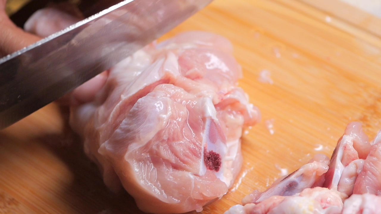 Close-up of Hand Cutting Raw Chicken with a Knife