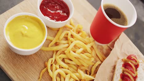 video of hot dog with mustard, ketchup and chips on a black surface