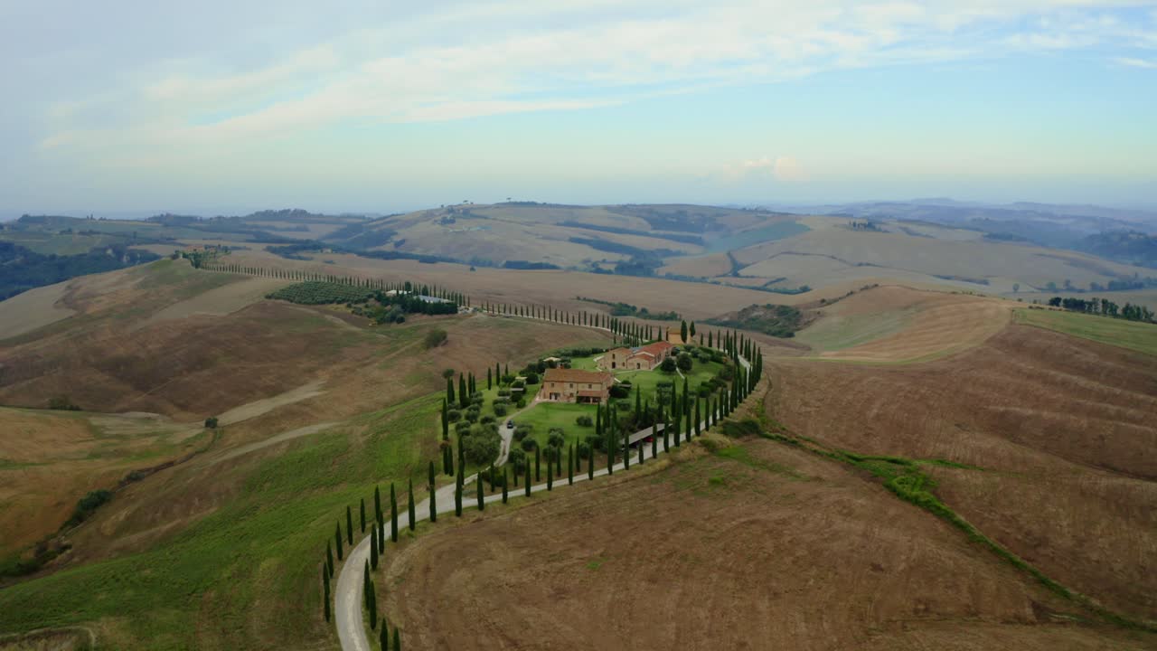Dry rolling farmland in Tuscany forms abstract patterns from above in warm midday light