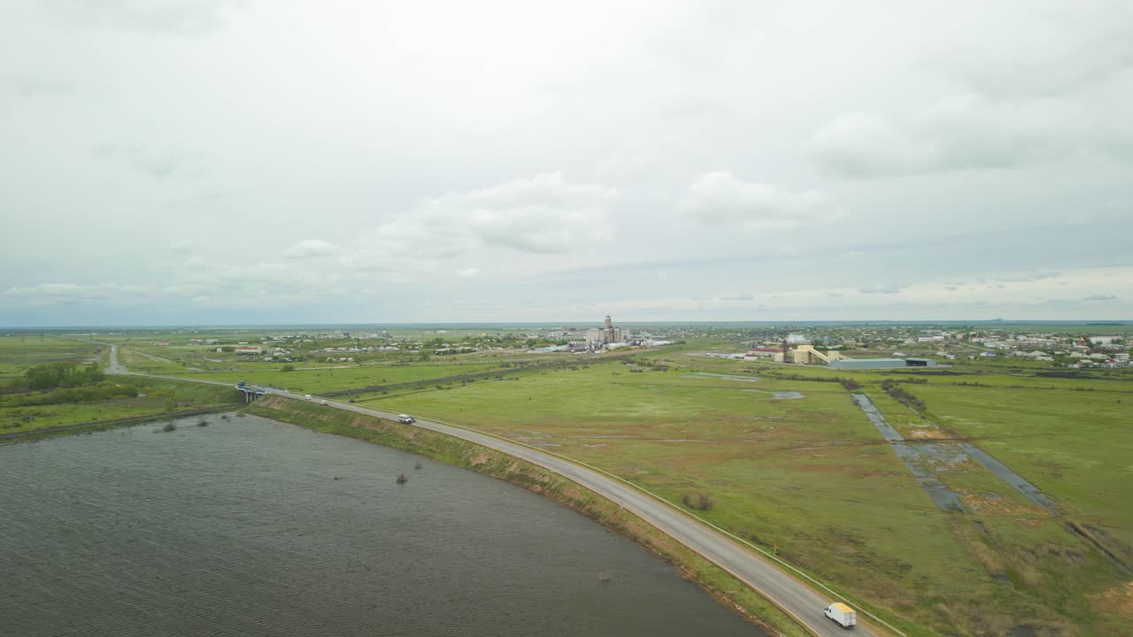 Aerial View of Rural Landscape with Road, Water, and Distant Industrial Town