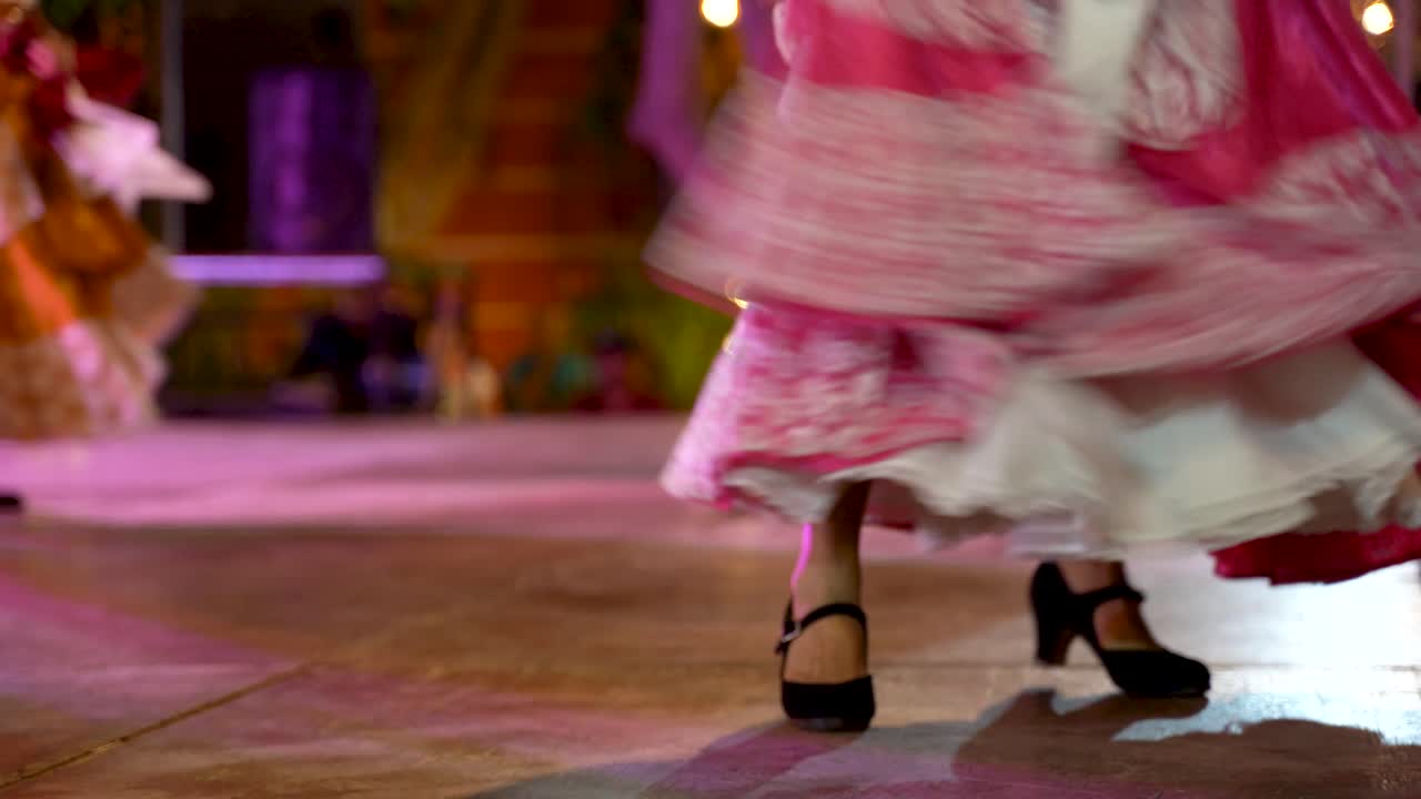 primer plano del vestido y los zapatos de la mujer mientras hace una danza folclórica mexicana en el escenario