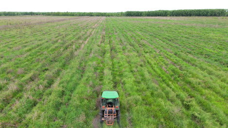 aerial drone tracks vehicle, tractor spraying fertilize on agricultural fields