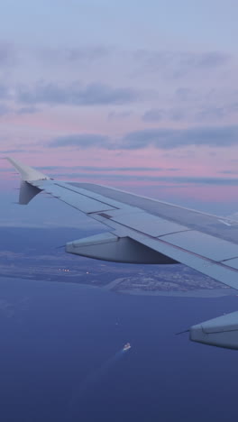 view from a plane window of the sky at sunrise with the wing of the plane in shot in vertical