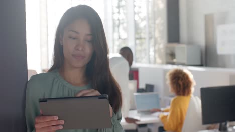 Portrait-of-happy-asian-casual-businesswoman-using-tablet-in-sunny-office,-copy-space,-slow-motion