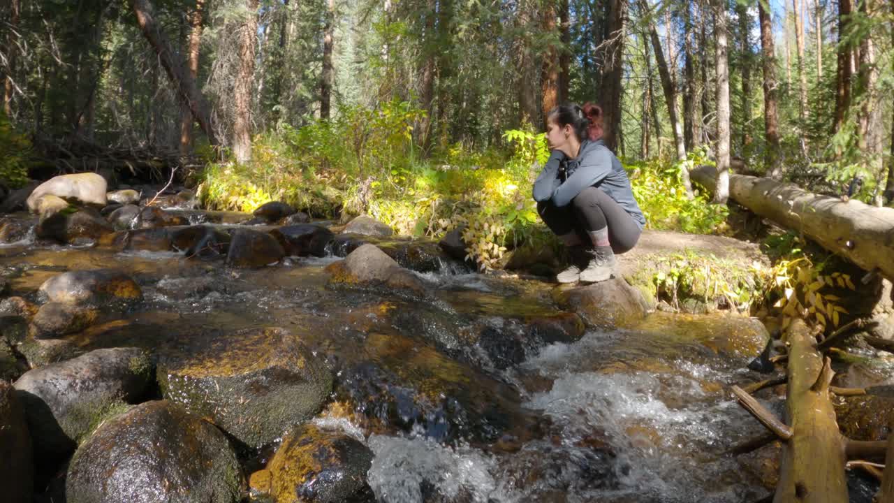 excursionista sentada junto al pensamiento del arroyo de montaña de colorado, estático