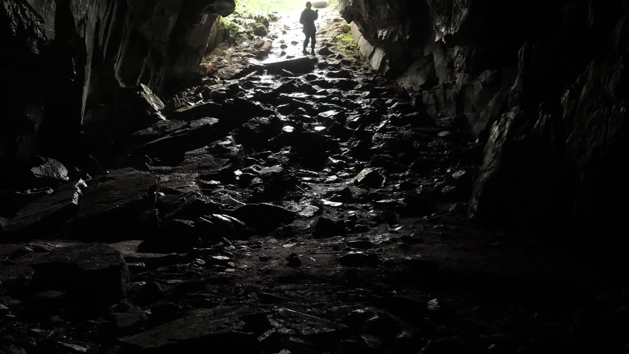 어두운 동굴 입구를 탐사하는 사람