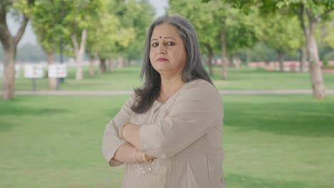 Portrait-of-Indian-old-woman-standing-crossed-hands-in-park