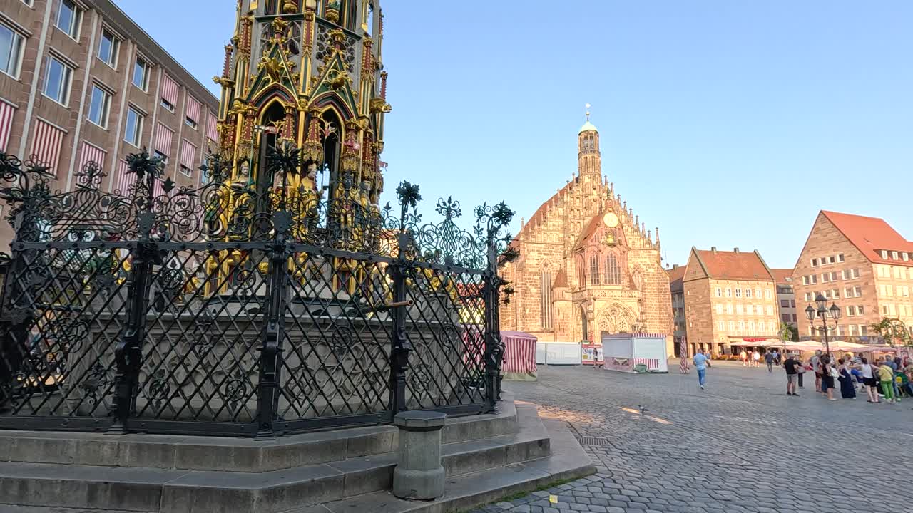 Person walking by ornate historic fountain in Nuremberg’s main square at golden hour