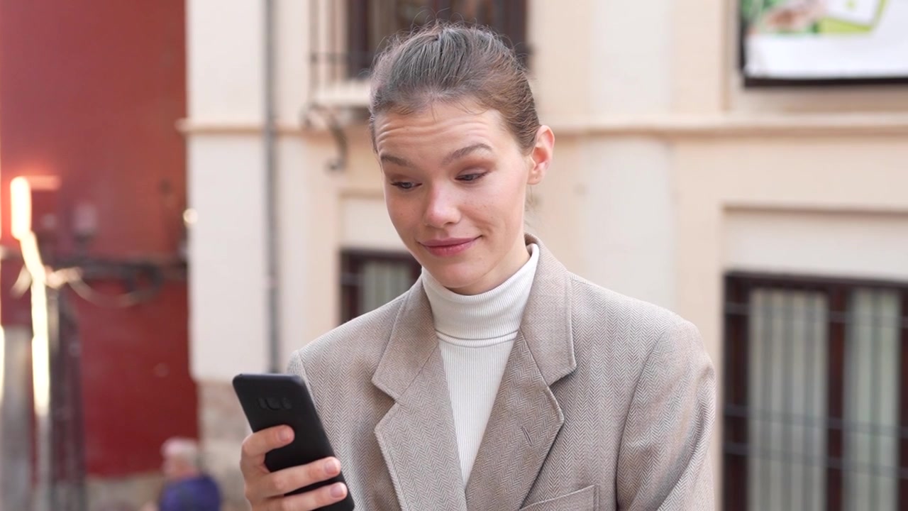 Una giovane donna usa il suo smartphone all'aperto in un'area urbana, evidenziando il suo stile di vita moderno.