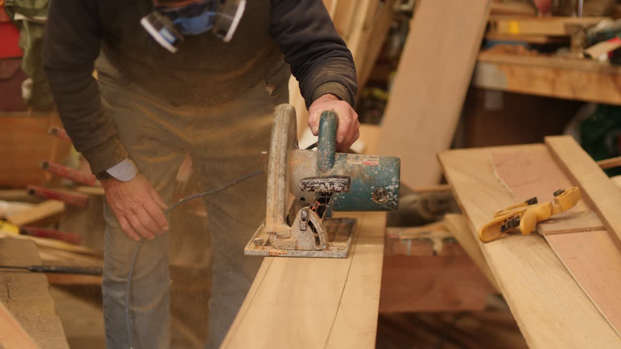 A craftsman cuts a wooden board with an electric saw.