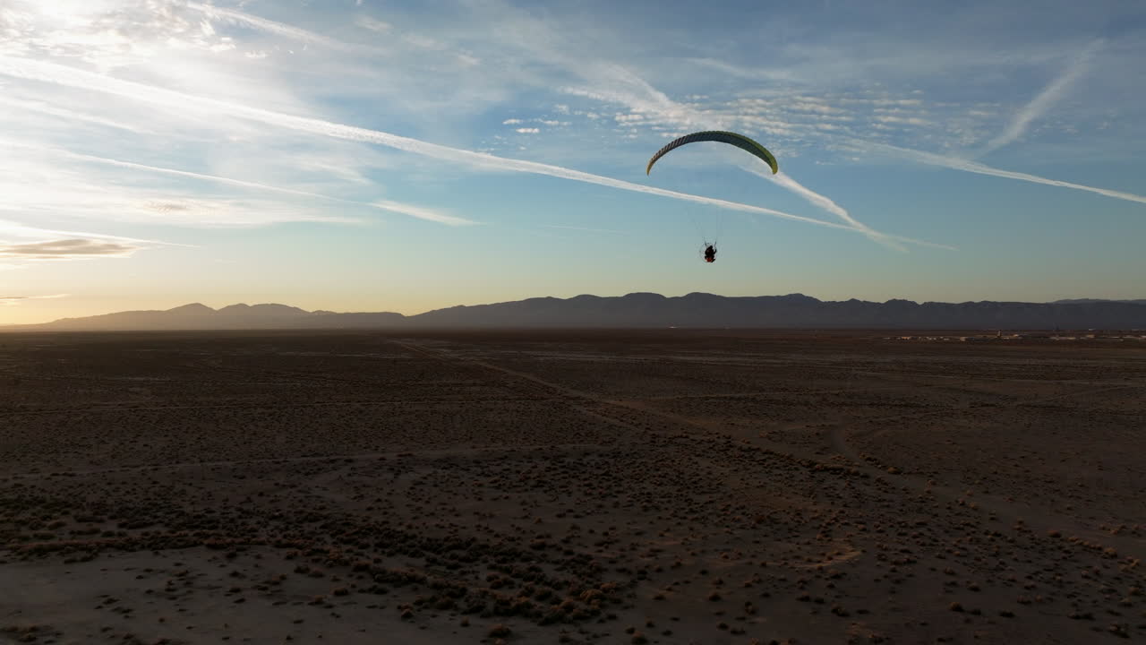 silueta de un parapente motorizado que vuela sobre el desierto de mojave al atardecer