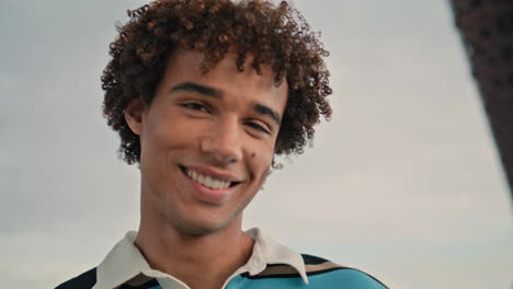 happy student dancing outdoors portrait. curly hair man looking camera at street