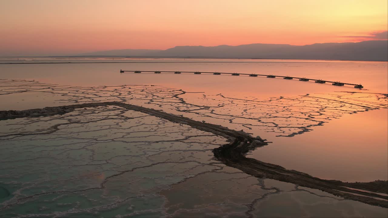 Aerial drone view on the dead sea of   an aqua color with beautiful red mountains in the background and a beautiful sunset