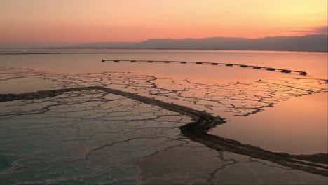 aerial drone view on the dead sea of   an aqua color with beautiful red mountains in the background and a beautiful sunset
