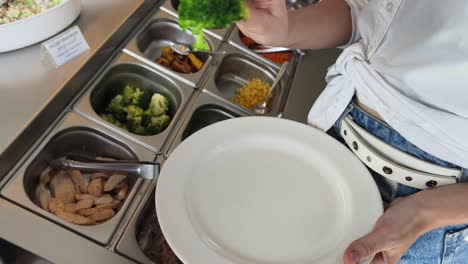 woman serving herself at a salad bar