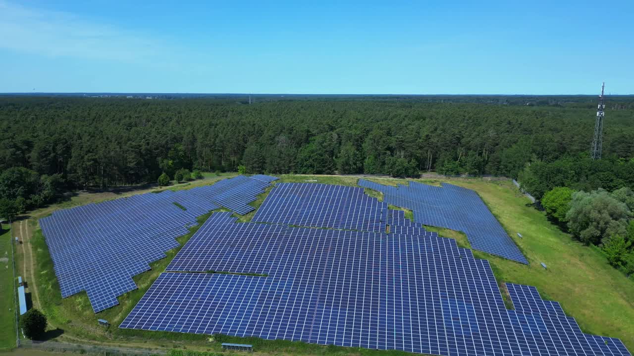 Photovoltaic panels providing clean energy in a solar farm on hill near a forest in Germany. Perfect aerial view flight panorama orbit drone