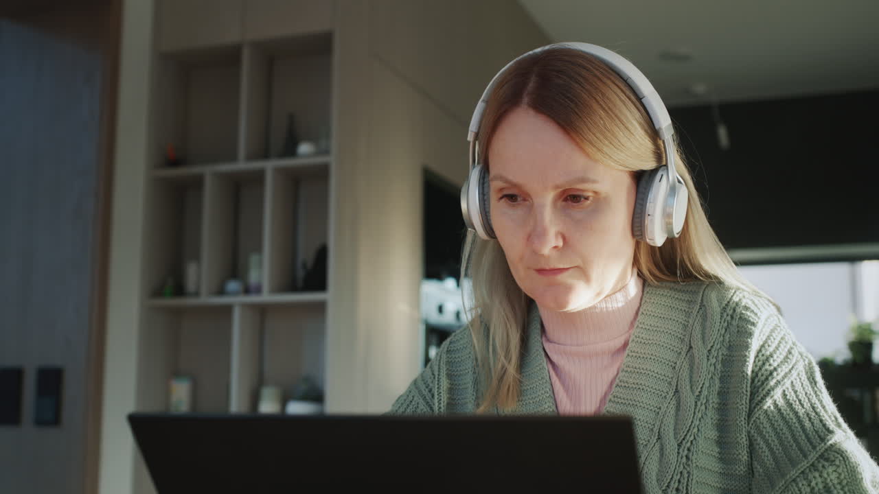 una mujer con auriculares usa una computadora portátil. trabajo desde casa concepto